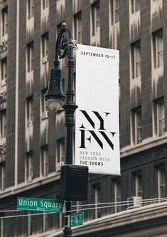 a street light with a sign hanging from it's side in front of a tall building