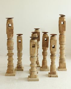 several wooden candlesticks are lined up against a white background, with one candle in the middle