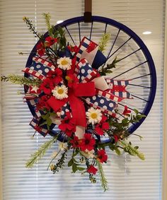 a red, white and blue wreath hanging on the side of a window