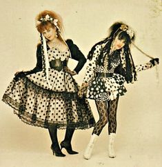 two women dressed in polka dot dresses and holding umbrellas, both wearing black and white