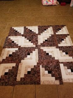 a brown and white quilt sitting on top of a floor