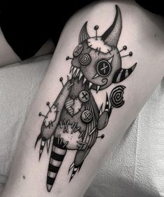 a woman's leg with a black and white tattoo design on her thigh, holding a candy cane