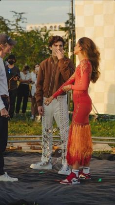 a woman in a red dress is standing on a skateboard with two other people