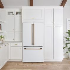 a white kitchen with wooden floors and cabinets