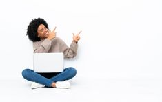 a woman sitting on the floor with her hands up in front of her laptop computer