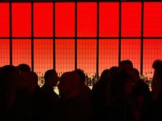 silhouettes of people standing in front of a large window with red squares on it