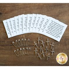 six pairs of nails and two sets of crosses on a wooden table next to some paper clips