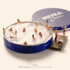 miniature people are playing in the water with a frisbee and other toys on a white surface