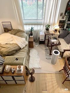 a living room filled with furniture next to a window covered in white blankets and pillows