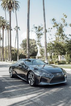 a black sports car is parked on the side of the road in front of palm trees