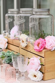 pink and white flowers are in mason jars on a table with other glass vases