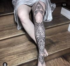 a woman's legs with tattoos on them sitting on the steps in front of stairs