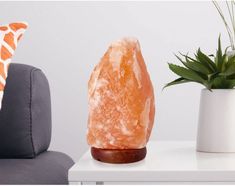 a large orange rock sitting on top of a white table next to a potted plant