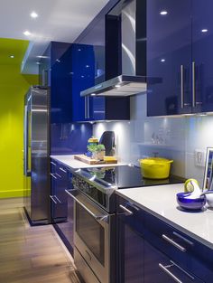 a kitchen with blue cabinets and stainless steel appliances in the center, along with a yellow bowl on the counter