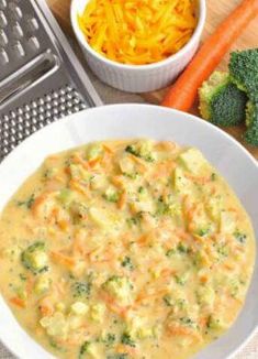 a white bowl filled with broccoli and cheese next to carrots