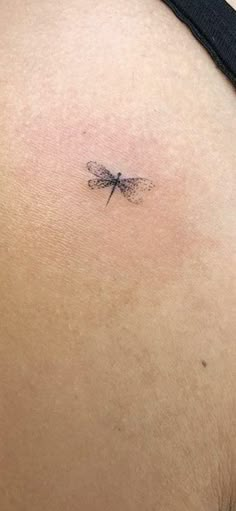 a small dragonfly tattoo on the back of a woman's stomach