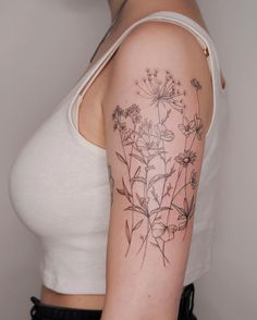 a woman with a tattoo on her arm has flowers growing out of the back of her shoulder