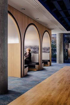 a person sitting on a bench in a room with wooden walls and blue carpeting