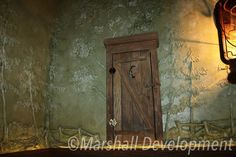 a wooden door sitting in the corner of a room next to a wall with a light on it