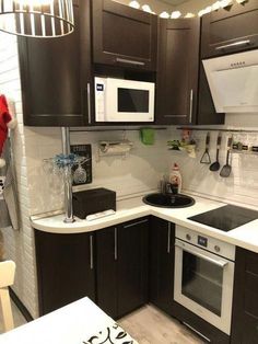 a kitchen with black cabinets and white counter tops, including a stove top oven and microwave