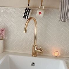 a white sink sitting under a faucet next to a wall mounted soap dispenser