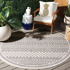 an outdoor area rug with pineapples on it and potted plants in the background