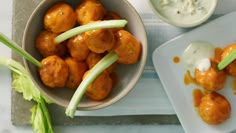 two bowls filled with food next to celery sticks and a bowl of sauce