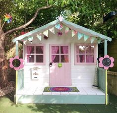 a pink and white play house with flowers on the front door is decorated in pastel colors