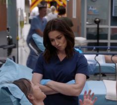 a woman in scrubs is standing next to another woman who is laying on a hospital bed