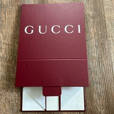 a red gucci book sitting on top of a wooden table next to a cell phone