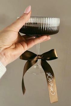 a hand holding a wine glass with a ribbon around it