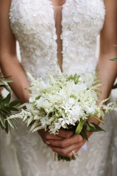 the bride is holding her bouquet of white flowers