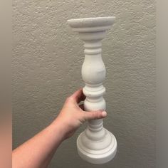 a person holding a white candle holder in their hand