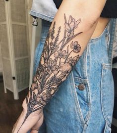 a woman's arm with flowers and leaves on it