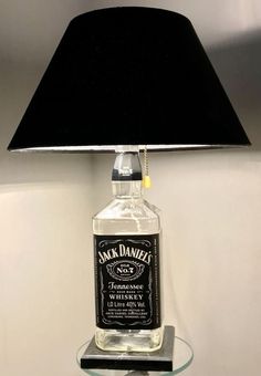 a bottle of jack daniels whiskey on a glass table with a black lamp shade over it