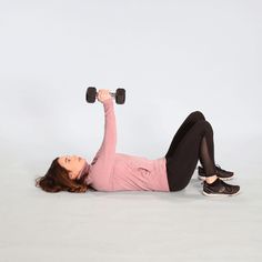 a woman is laying on the ground with two dumbbells in her hands and one arm behind her head