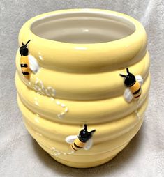 a yellow vase with three bees on it