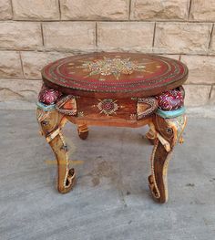 an elephant shaped wooden table sitting on top of a cement floor next to a brick wall