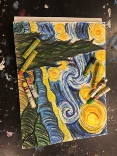 some crayons are laying on top of a painting with the starry night