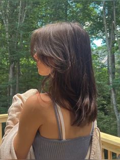 the back of a woman's head and shoulder, with trees in the background