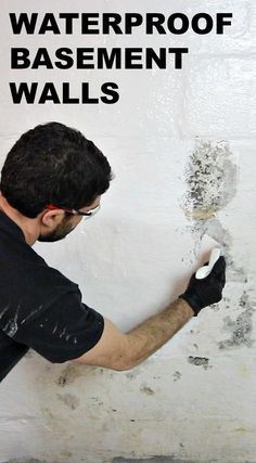 a man in black shirt and gloves painting a wall with waterproof basement walls