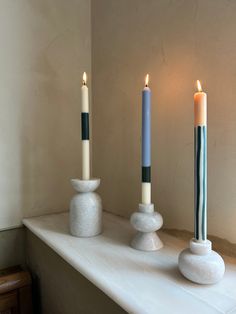 three candles sitting on top of a white mantle