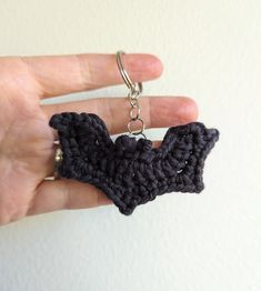 a crocheted bat keychain being held by a person's hand