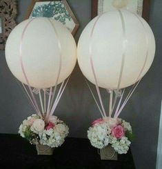 two white balloons sitting on top of a table next to vases filled with flowers