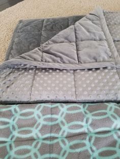 two blankets laying on top of each other next to a pillow and blanket cover with circles