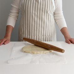 a person standing in front of a doughnut on a table with a rolling pin