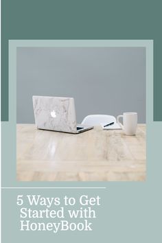 a laptop computer sitting on top of a wooden table next to a cup and saucer