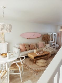 a living room filled with furniture and a pink surfboard hanging above the couches