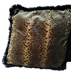 a leopard print pillow with black fringes on the bottom and an animal print pattern on the back