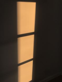 the shadow of a window on a wall in an empty room with light coming through it